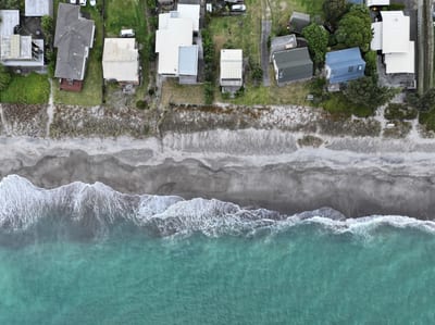 An aerial view of a beach with houses and waves crashing on the shore.